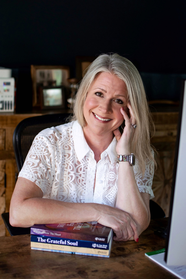 Lindy smiling at her desk with her hand resting at her temple.